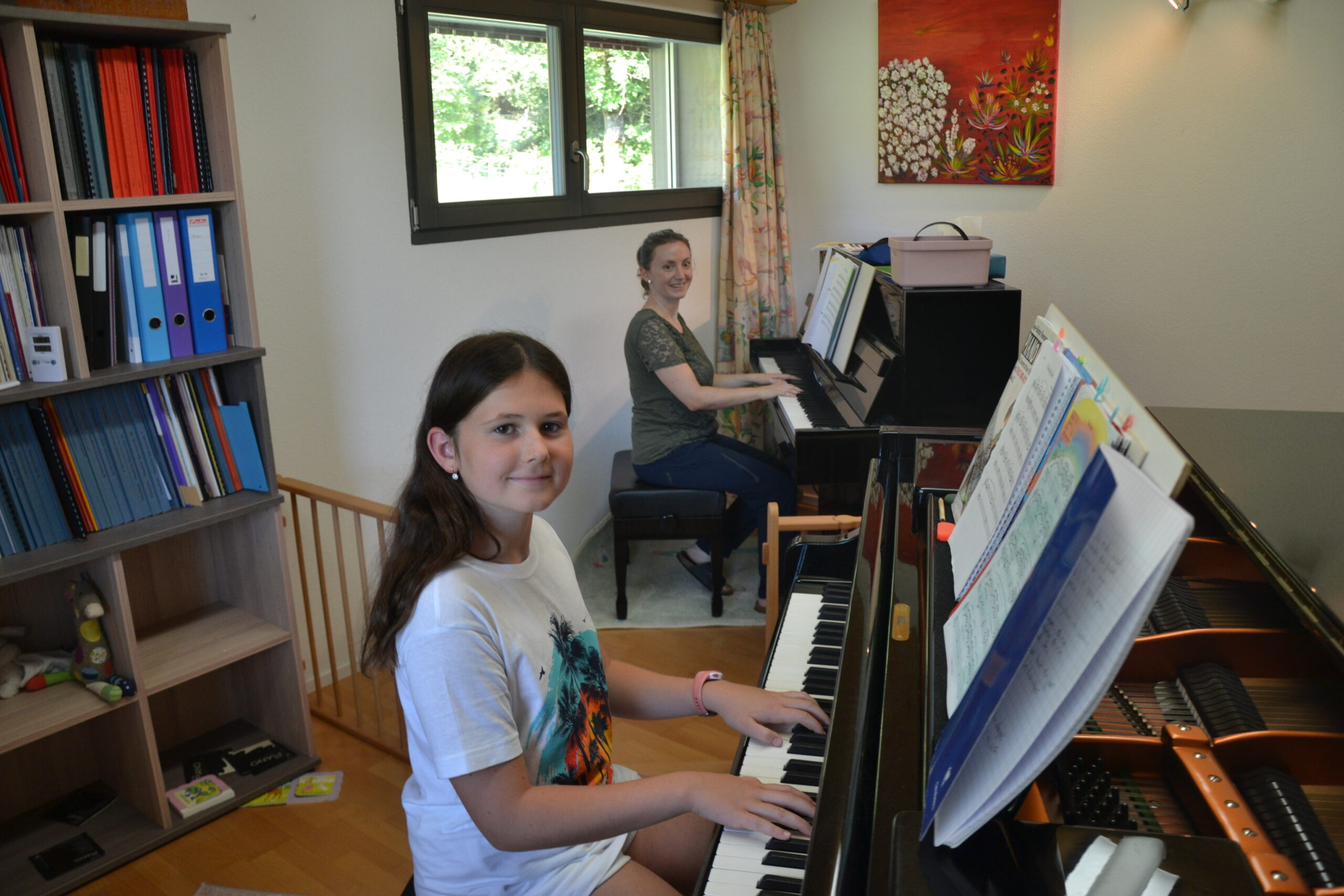 Linda Gysin aus Valangin (Neuchâtel) am Klavier im Hintergrund und ein junges Mädchen am Klavier im Vordergrund.